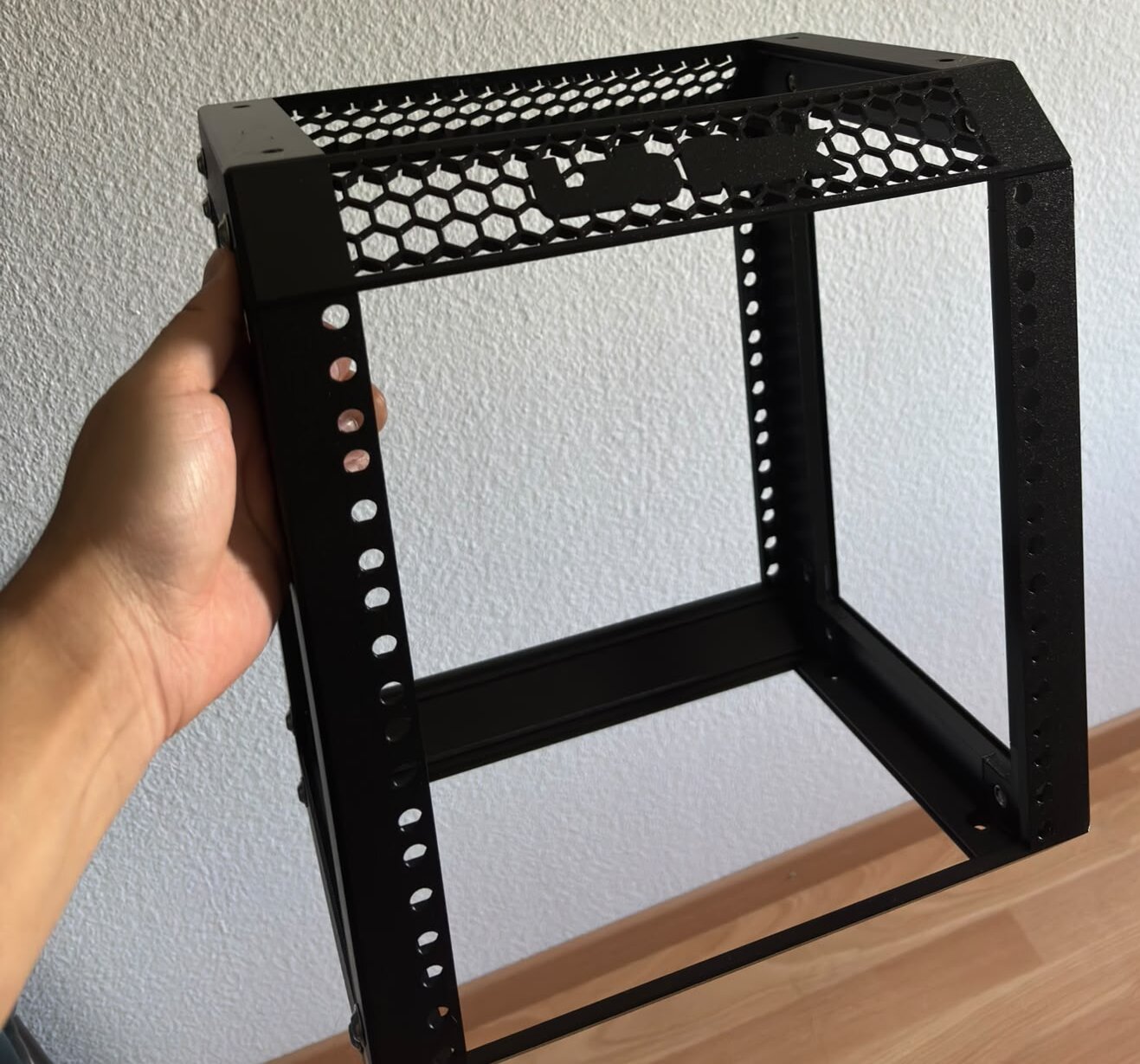Das fertig zusammengebaute, noch leere schwarze 10-Zoll-Rack wird mit einer Hand gehalten.