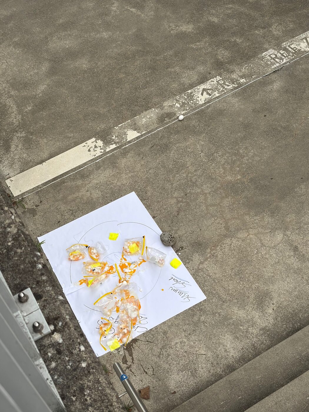 Zielscheibe aus Papier auf Beton, darauf zerplatzte Eier in Plastikbeuteln und Klebebandresten.
